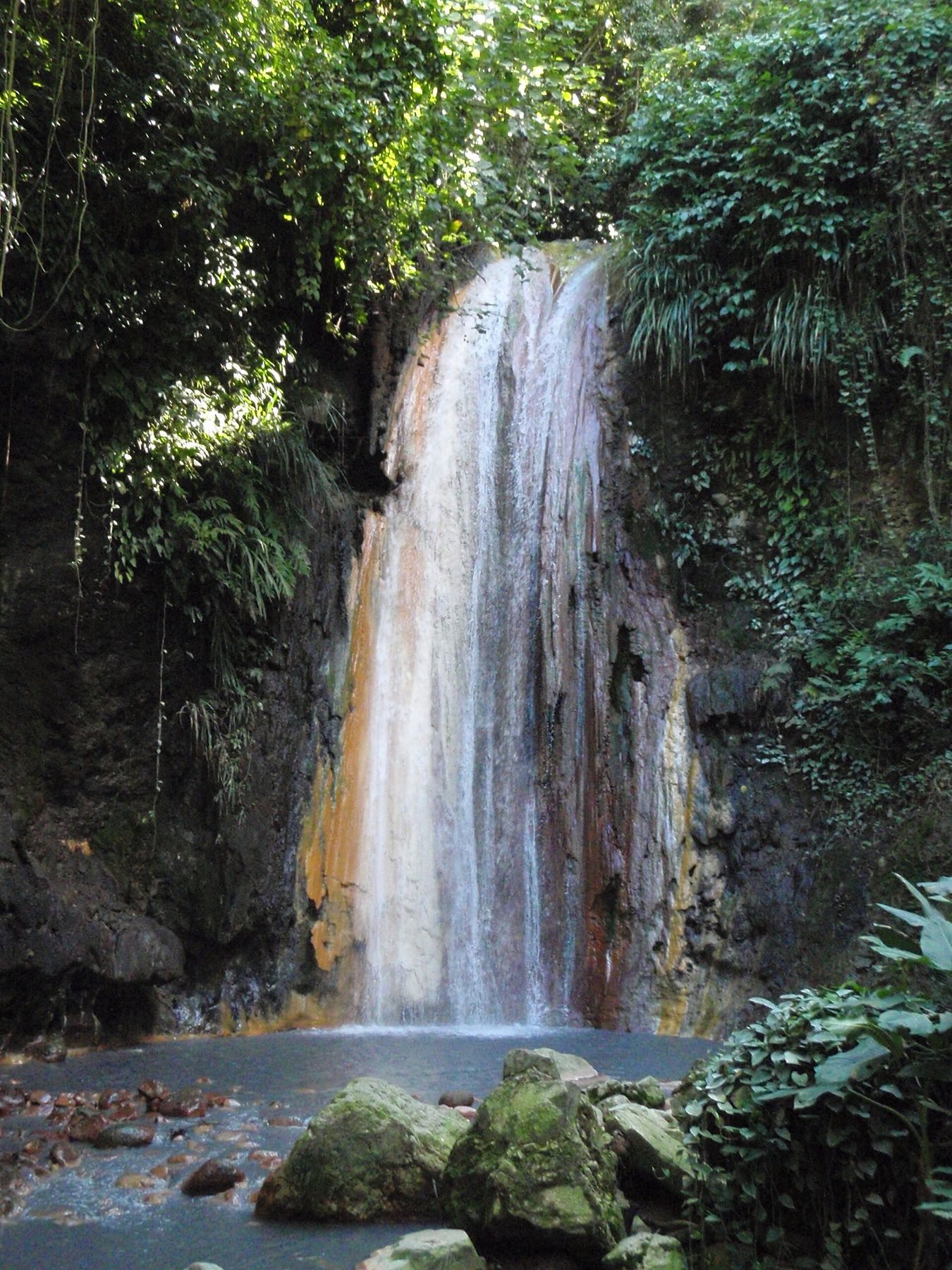 Diamond Falls cascading over colourful mineral-stained rock in a garden
